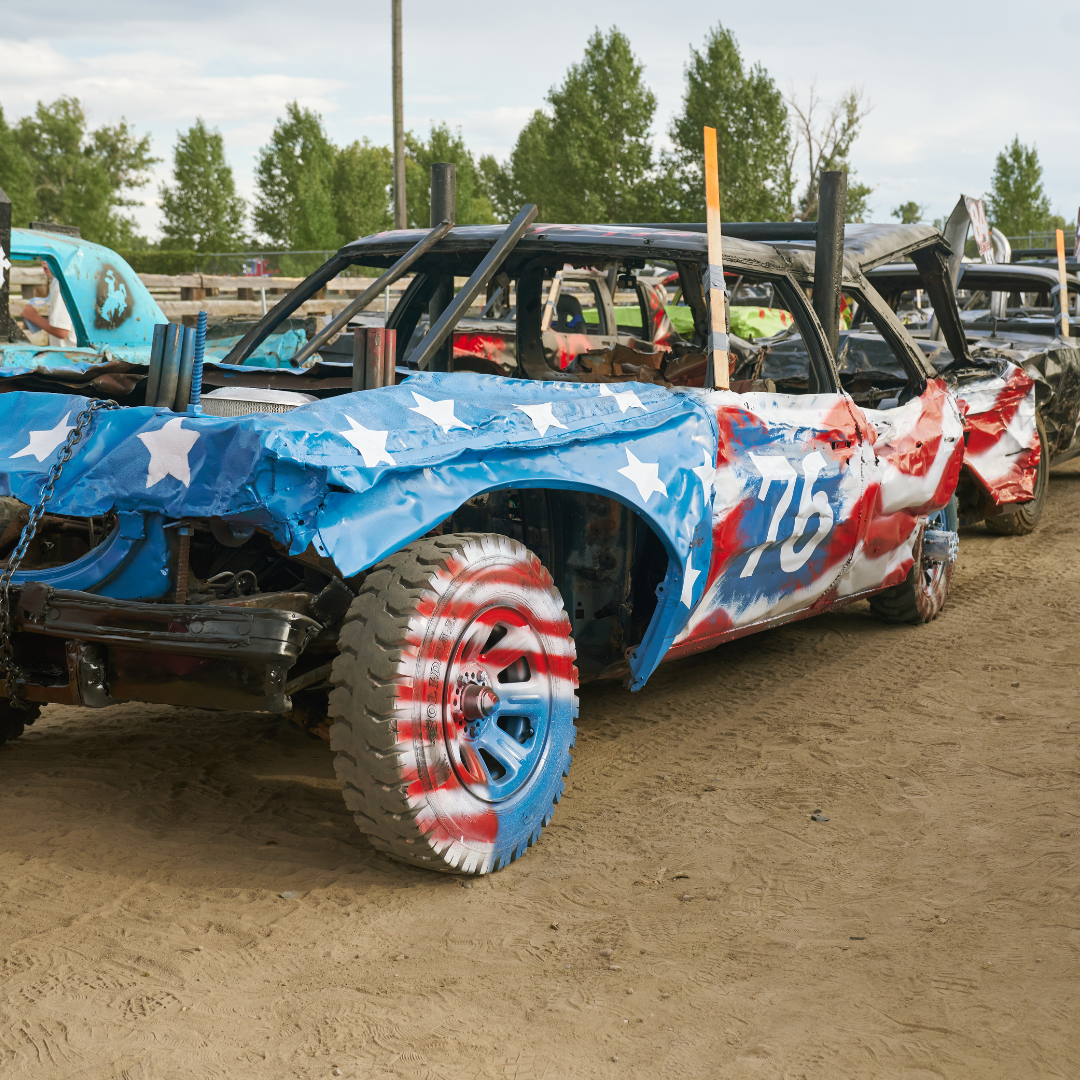 Patriotically painted demolition derby cars lined up on the dirt arena at the Wyoming State Fair.