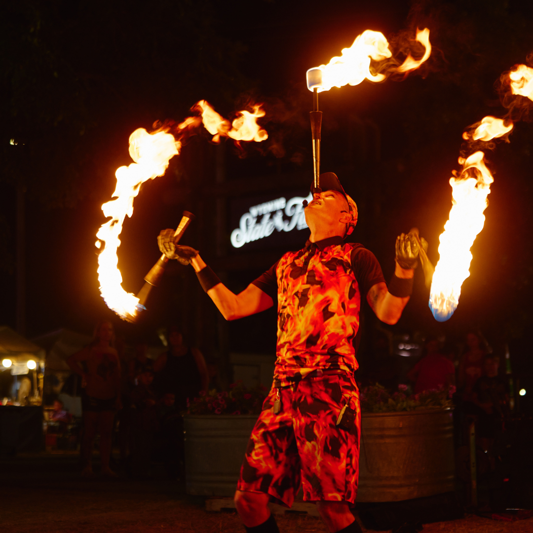 Fire performer juggling flaming torches during an evening entertainment show at the Wyoming State Fair.