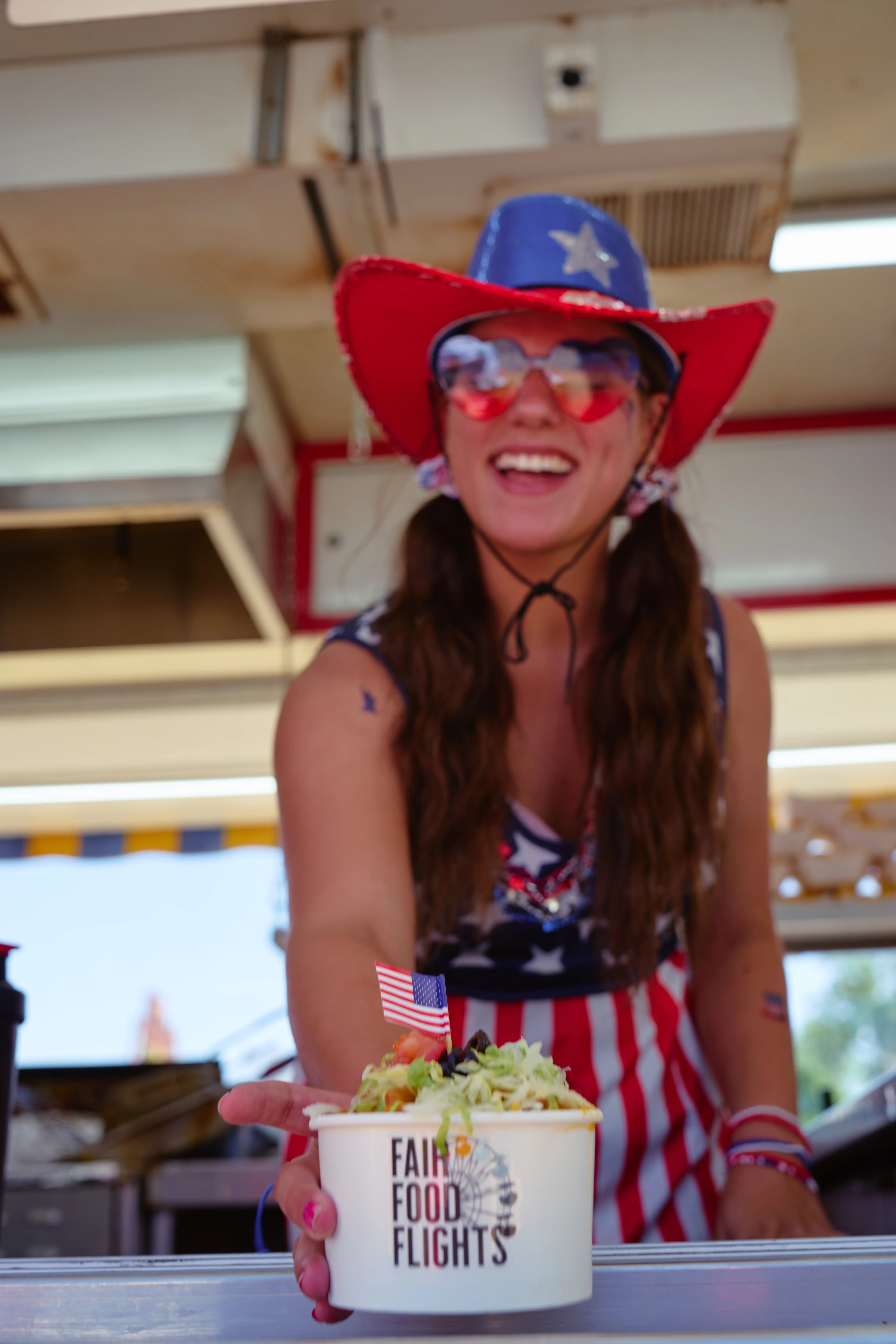 Vendor serving a Fair Food Flights sample cup at the Wyoming State Fair food stand.