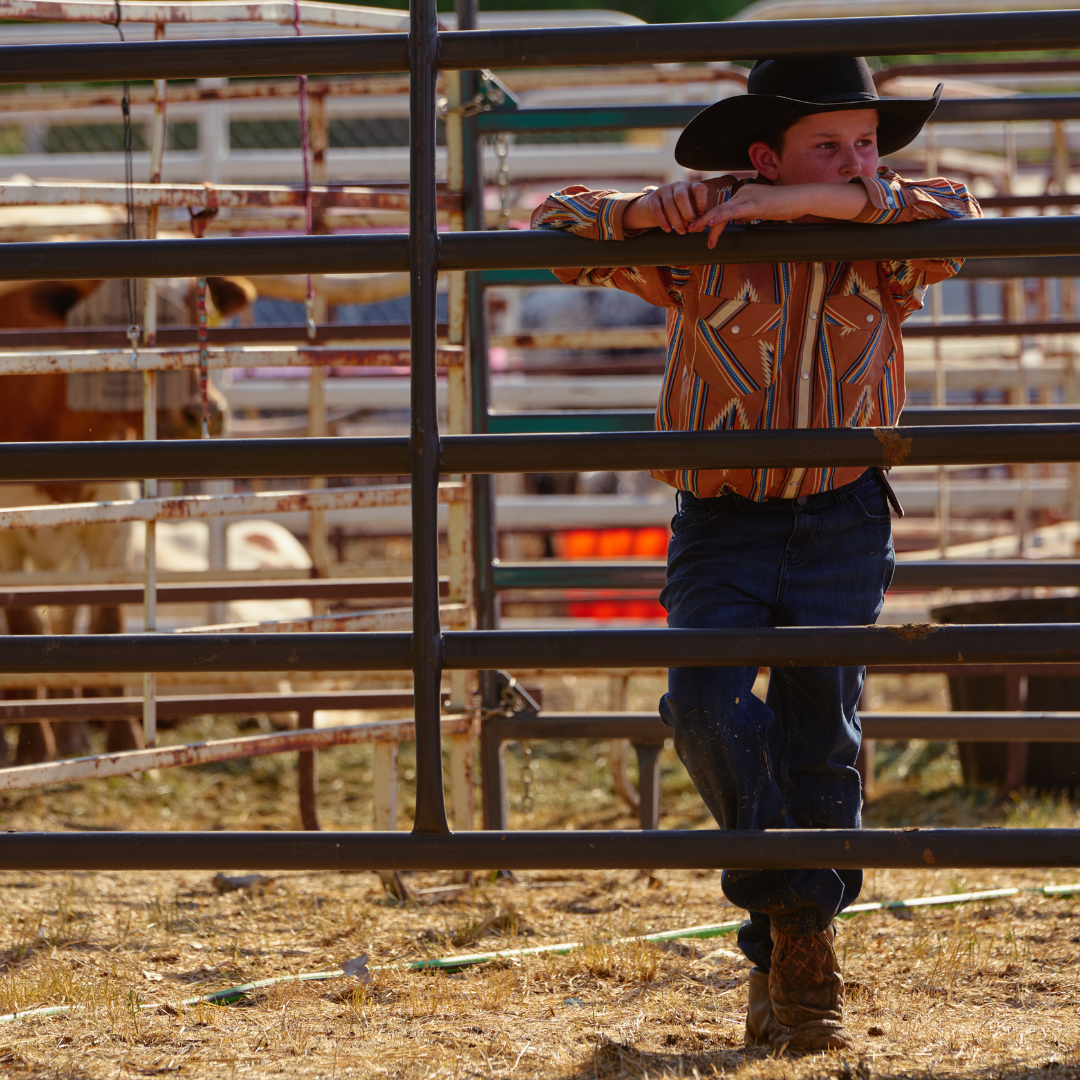 Young boy in a cowboy hat leaning on a fence in the livestock area at the Wyoming State Fair.